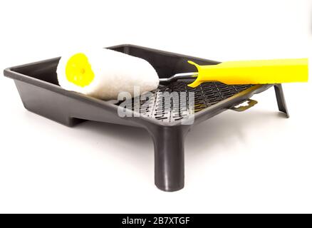 A clean paint roller rests on a black paint tray. Isolated on white background with clipping path. Stock Photo