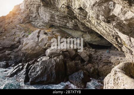 Tourists visiting the Grotto Golitsyn (Pop, Chaliapin grotto) - a large natural grotto, knocked out by sea waves in the mountain Koba-Kaya (Cave) near Stock Photo