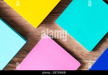 Composition of various colored notebooks on wooden background. The notebooks are blue, mint green, pink, blue and yellow. Aerial view Stock Photo