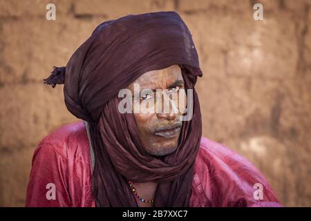 Tuareg nomad old man in traditional turban portrait close up clay wall Stock Photo