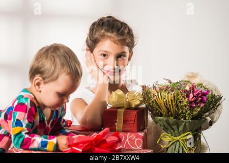 Little cute boy gives a bouquet to his charming older sister on International Women's Day. Concept of women's holidays and gifts Stock Photo