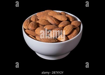 Peeled almonds in a white bowl, isolated on a black background. Image Stock Photo