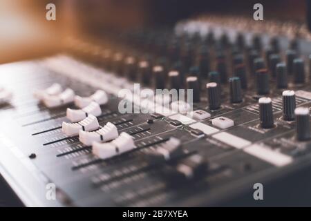 Sound mixer. Professional audio mixing console with lights, buttons, faders and sliders. Stock Photo