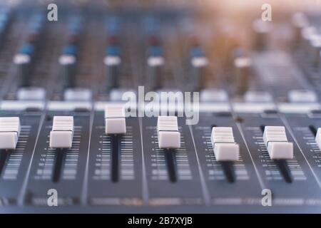 Sound mixer. Professional audio mixing console with lights, buttons, faders and sliders. Stock Photo