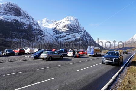 Sun and snow in the Scottish Highlands, A82 road at Glencoe seen here being affected. Visitors carpark at the Three sisters ridge. Scotland. Stock Photo