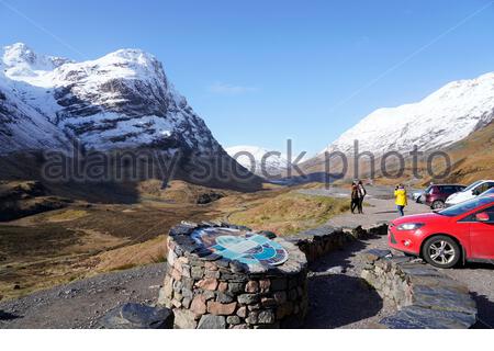 Sun and snow in the Scottish Highlands, Glencoe seen here being affected. Visitors and carpark at the Three Sisters Ridge. Scotland. Stock Photo
