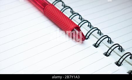 Close up of  lines notebook and red pencil. Spiral notepad paper background. Stock Photo