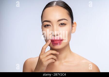 Smiling Asian woman is putting lip patches Stock Photo