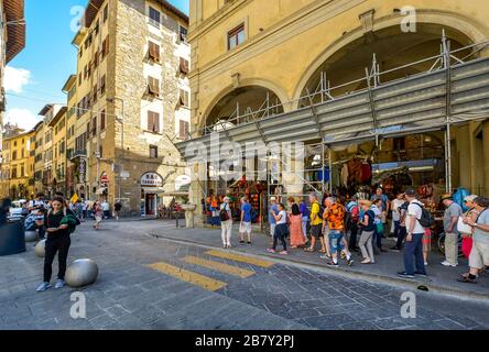 A group of tourists pass souvenir, leather and gift shops in the historic center of Florence, Italy Stock Photo