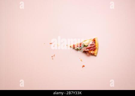 Pizza prosciutto single slice with cheese and arugula on pink background. Last piece of ham pizza flat lay. Italia popular food. Stock Photo