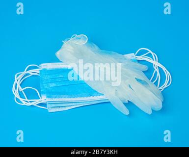 disposable gloves and stack of medical masks made of non-woven material with white rubber bands on a blue background, protective accessory for the res Stock Photo