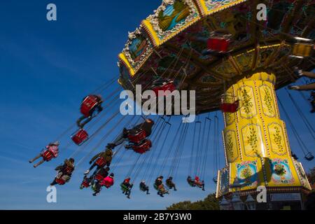 chairoplane, chain caroussel at traditional, historic fun fair in Bremen, Germany on a sunny day with blurred People and blue sky in the background Stock Photo