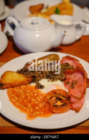 White board with full Scottish breakfast with bacon, fried egg, beans, tomato, roasted sausage, pudding, hash browns and haggis Stock Photo