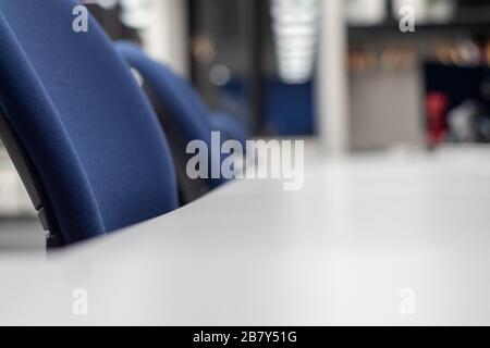 Chairs are lined up at a long desk in a co-working office space. Stock Photo