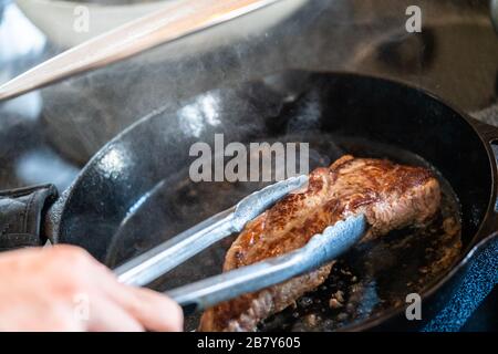 How to cook new york strip steak on electric stove Frying New York Strip Steak In Cast Iron Frying Pan Over The Electric Stove Stock Photo Alamy