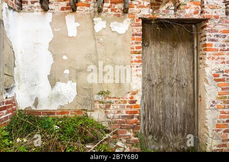 Boarded up doorway in wall of crumbling stucco and bricks. Stock Photo