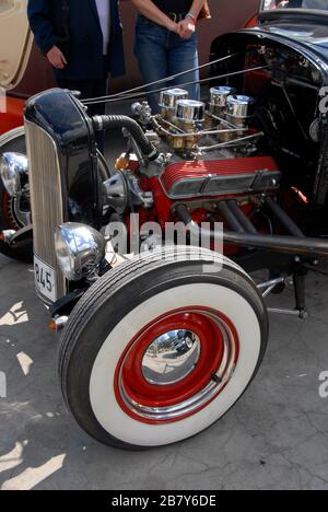 Car with bonnet cover removed and red-painted wheel trims and white-walled tyres on display at small local motor show, England Stock Photo