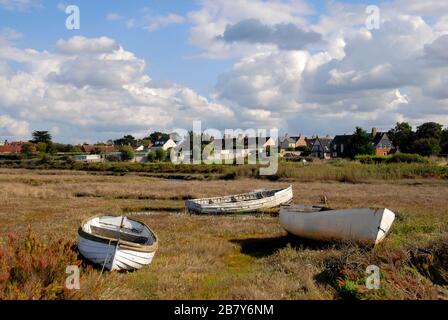 Three white dinghies on shore at low tide, Brancaster Staithe, Norfolk, England. Stock Photo