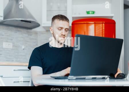 Handsome Pensive Businessman Working On Laptop from Home. Concept Of Working And Living In Quarantine. Coronavirus. Modern Technologies. Cozy Home Int Stock Photo