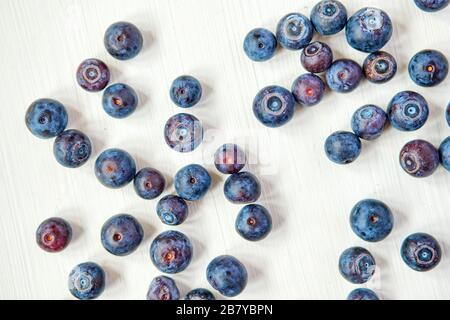 Blueberries scattered on a white wooden background. Top view Close up. Stock Photo