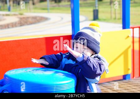 POZNAN, POLAND - Mar 08, 2020: Young boy playing with a blue plastic drum at a playground in the Rataje park. Stock Photo