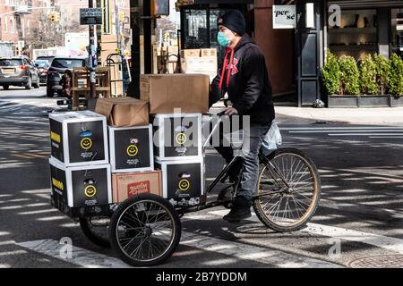 Brooklyn, USA . 18th Mar, 2020. A bike delivery driver wearing a face mask in the Borough Park neighborhood of Brooklyn on March 18, 2020. At least 100 people have tested positive for Coronavirus in the predominantly Hasidic community since Friday. (Photo by Gabriele Holtermann-Gorden/Sipa USA) Credit: Sipa USA/Alamy Live News Stock Photo