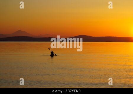 Kayaker paddles into Haro Strait at sunrise on a calm day. Stock Photo