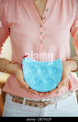 Closeup on woman at home in sunny spring day showing blue chicken shaped plate for eggs. Stock Photo