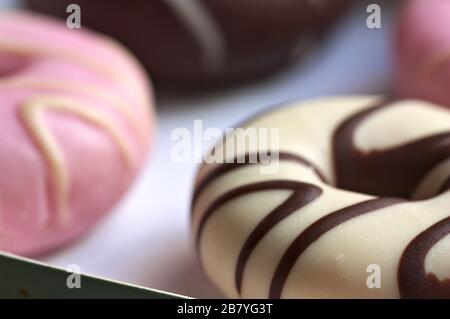 Closeup of a box with some donuts of different flavors and colors such as strawberry and chocolate Stock Photo