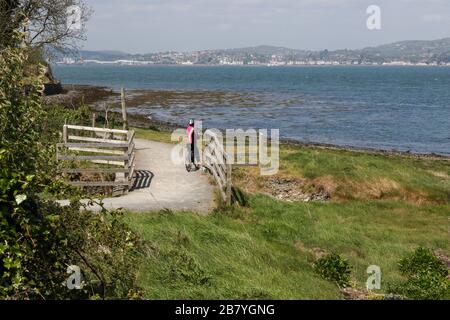 A female cyclist on a warm sunny spring day on the Great Eastern Greenway, County Louth looking across Carlingford Lough towards Warrenpoint,. Stock Photo