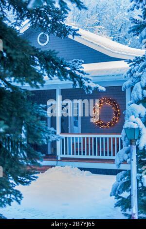 Illuminated Christmas wreath on house during winter Stock Photo