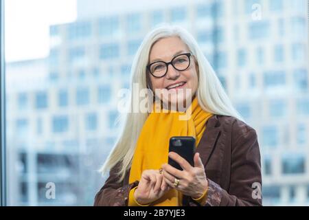 Smiling businesswoman with smartphone in office Stock Photo