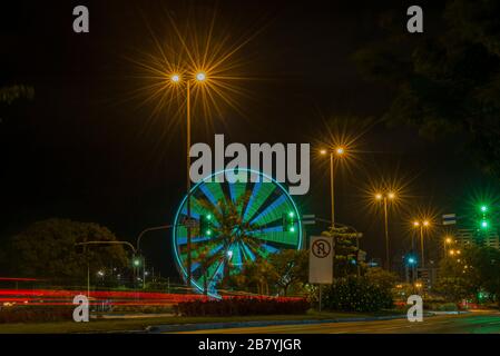 Long exposure of colorful ferris wheel and light trails on the expressway road at night. Time exposure of traffic lights on avenue in Florianopolis. C Stock Photo