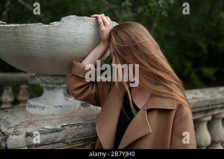 Young woman holding broken flower pot on stone banister Stock Photo