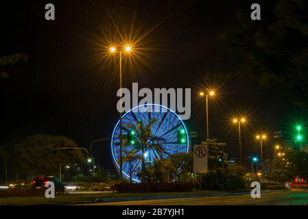 Long exposure of colorful ferris wheel and light trails on the expressway road at night. Time exposure of traffic lights on avenue in Florianopolis. C Stock Photo