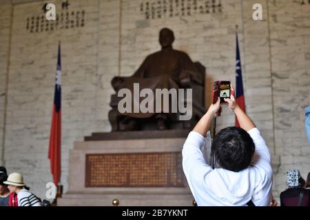 A tourist takes a photo of the Chiang Kai-shek monument in Taipei using his mobile phone Stock Photo