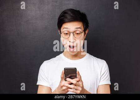 Technology, messaging and people concept. Close-up portrait of amazed and excited male student receive positive reply via messages in mobile phone Stock Photo