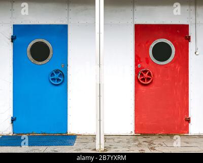 colorful blue and bright red painted door with porthole. metallic entrance doors with round windows Stock Photo