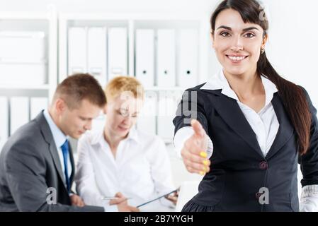 Beautiful smiling business woman in suit offering hand to shake Stock Photo