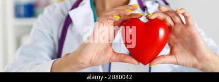 Female medicine doctor's hands holding red toy heart Stock Photo
