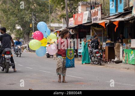 Eklingji, India - March 15, 2020: Child (girl) begger selling balloons to tourists in the middle of the street in rural india Stock Photo