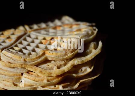 Fresh homemade waffles are stacked against a dark background with space for text Stock Photo
