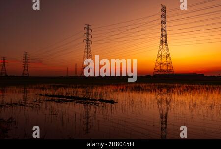 High voltage electric pylon and electrical wire with sunset sky. Electricity poles. Power and energy concept. High voltage grid tower with wire cable Stock Photo