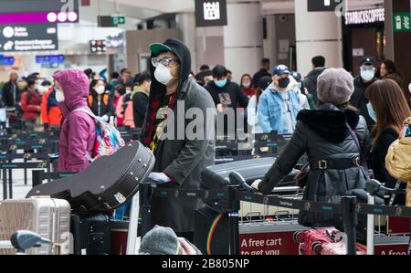 Toronto, Canada. 18th Mar, 2020. Travellers line up to check in at Terminal 3 of Pearson International Airport in Toronto, Canada, March 18, 2020. Canadian Prime Minister Justin Trudeau announced that the Canada-U.S. border will close to all non-essential travel, but shipments, trade and commerce will not be affected by the new restriction at the Canada-U.S. border. Credit: Zou Zheng/Xinhua/Alamy Live News Stock Photo