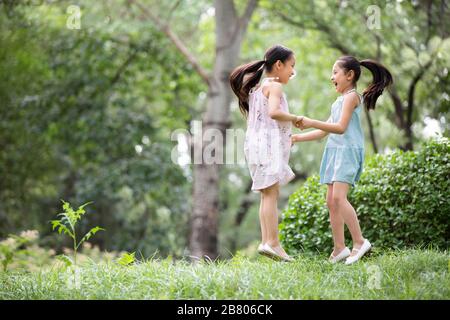 Two Chinese girls playing on grass Stock Photo