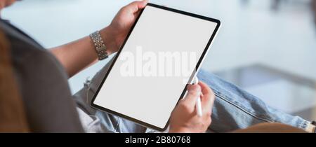 Cropped shot of a man sitting at modern living room and using vertical blank screen digital tablet with stylus pen Stock Photo