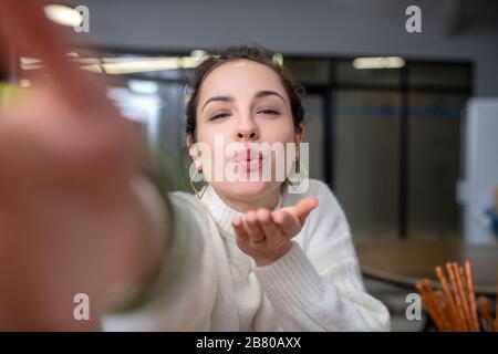 Beautiful young woman sending air kiss, holding out her hand Stock Photo