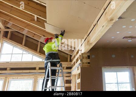 Construction worker thermally insulating eco wooden frame house Stock Photo