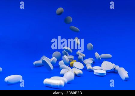 Falling white pills, tablets capsule on blue backround. Anti gravity concept Stock Photo