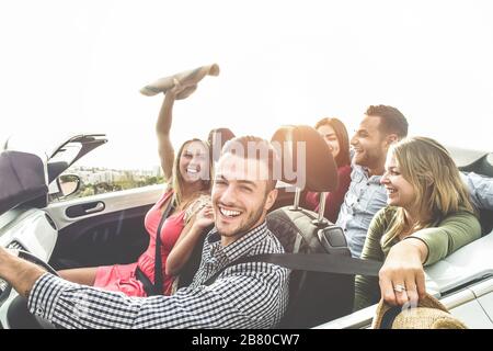 Happy friends having fun in convertible car on summer vacation - Young people laughing and smiling together during travel holidays - Youth lifestyle c Stock Photo